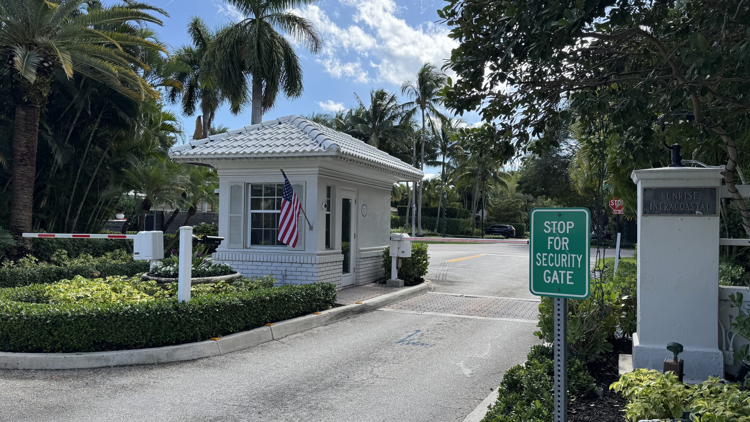 an entrance to Sunrise Intracoastal surrounded by palm trees and plants