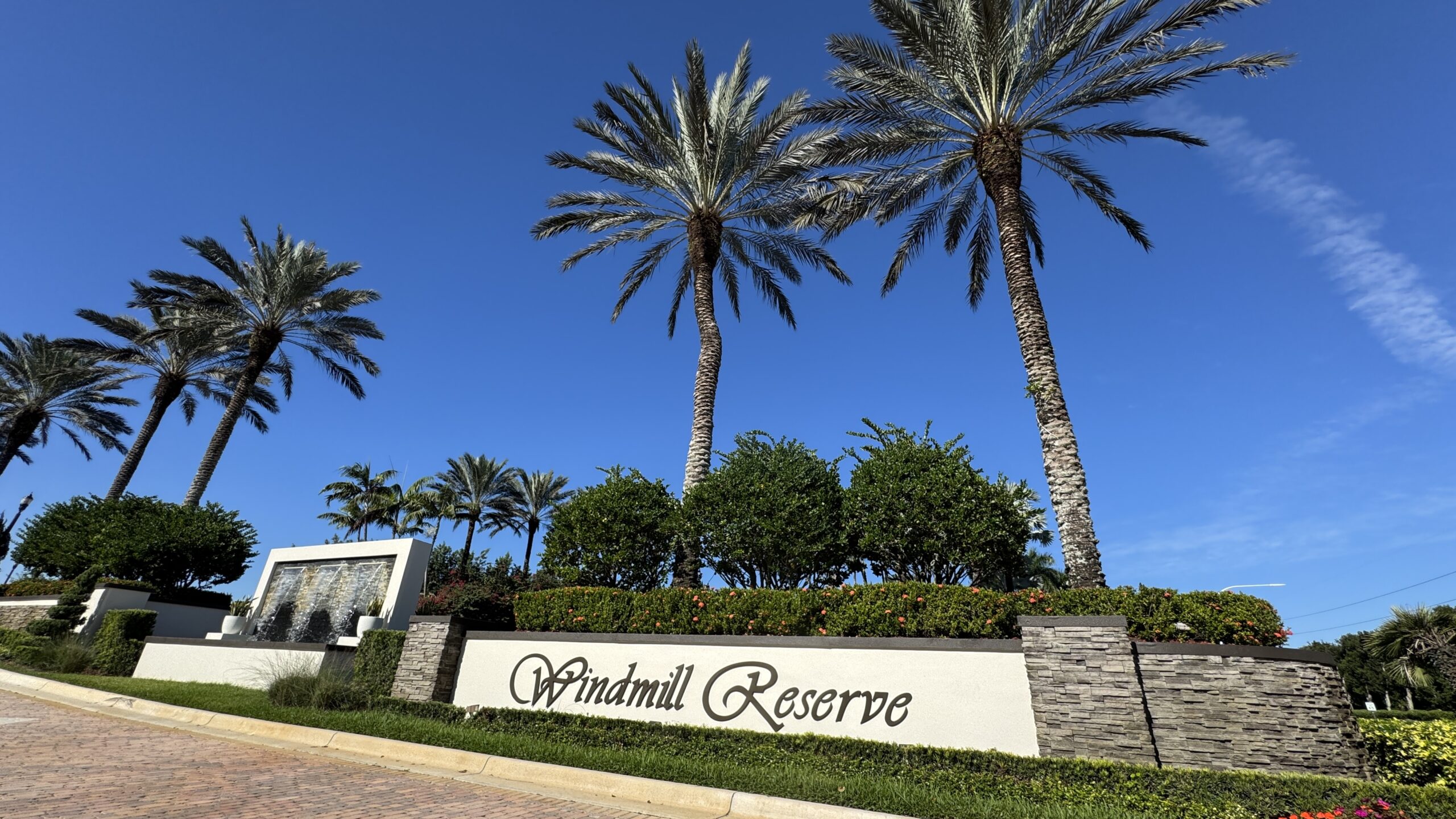 a neighborhood sign that says Windmill Reserve with palm trees and green trees